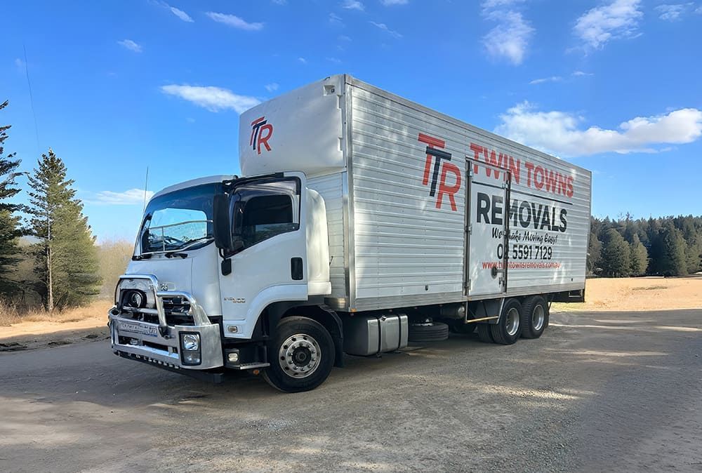 A White Truck Is Parked In A Dirt Lot — Twin Towns Removals Mid North Coast In Tuncurry, NSW