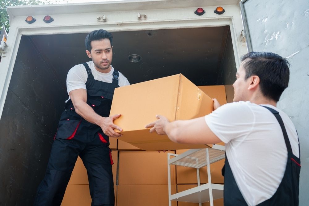 Two Movers Unloading Cardboard Box From Truck Mid North Coast