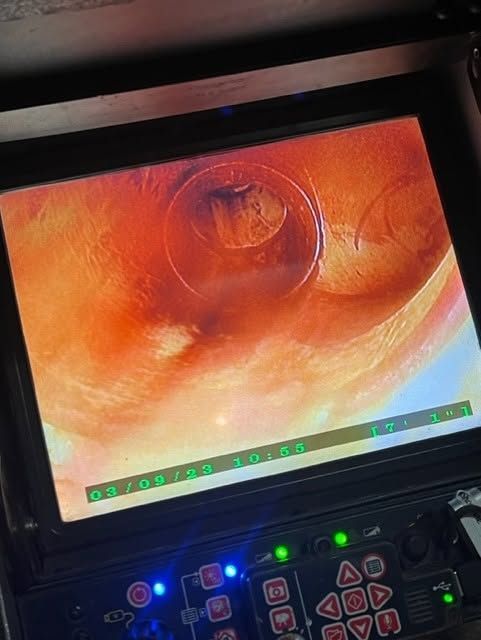 Endoscopic view of orange tissue on a monitor with control panel lights below