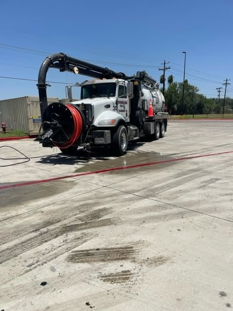 White utility truck with hose reel cleaning a concrete lot outdoors