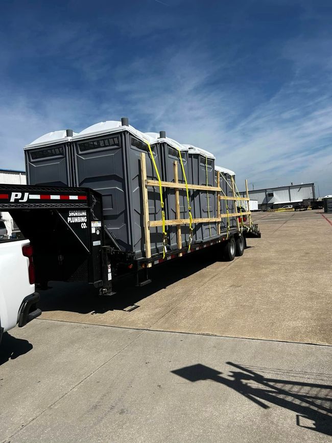 Flatbed trailer loaded with strapped black cargo crates in a sunny industrial lot