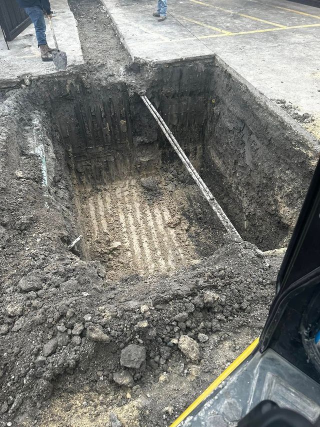 Open excavation trench with dirt walls and a metal brace at a construction site