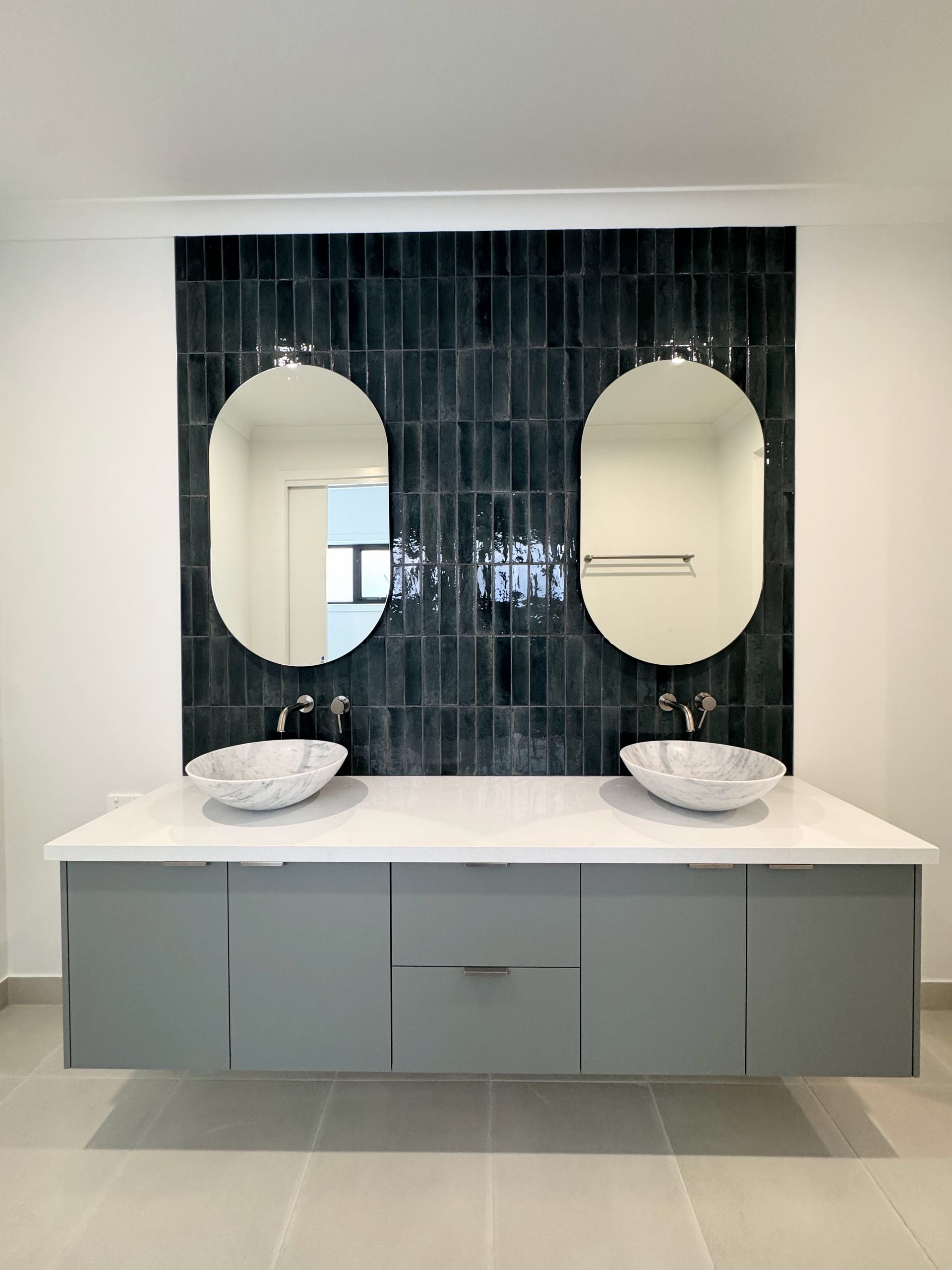 Modern bathroom with floating gray vanity, two sinks, oval mirrors, and teal tile backsplash — Crampton Painting & Decorating Pty Ltd In Maiden Gully, VIC