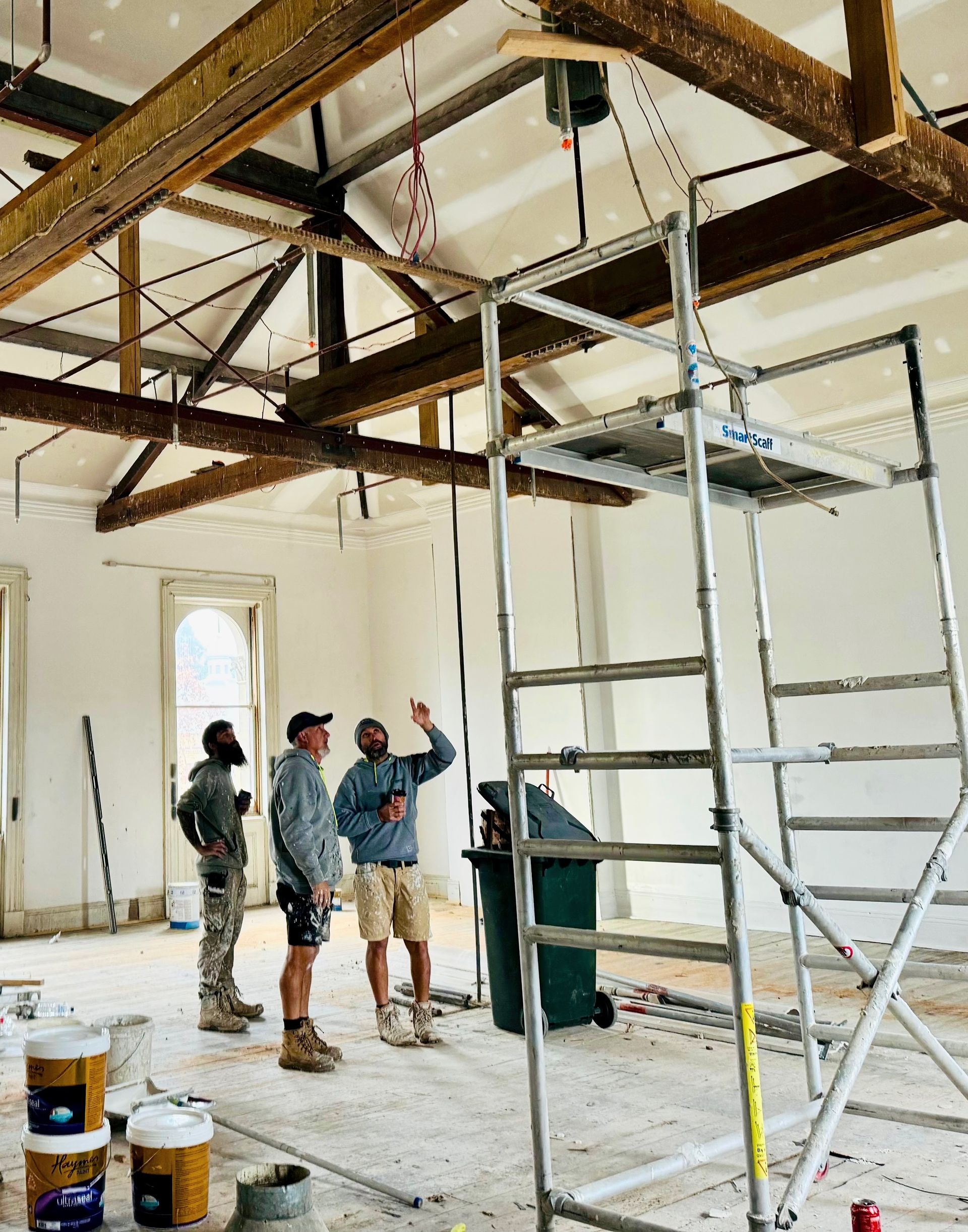 A Man Is Painting The Ceiling Of A Building — Crampton Painting & Decorating Pty Ltd In Maiden Gully, VIC