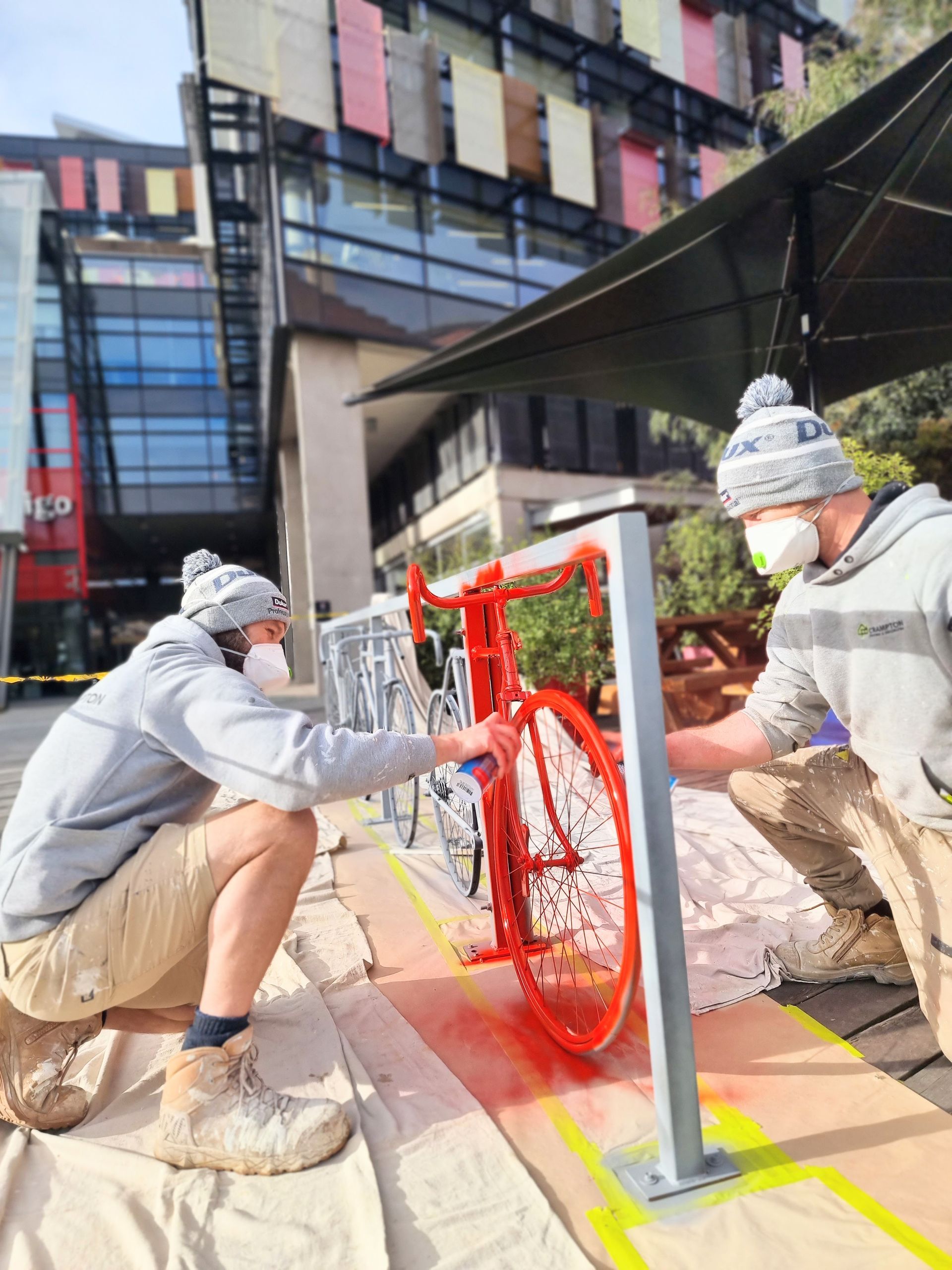 two painters are painting a red bike in bendigo — Crampton Painting & Decorating Pty Ltd In Bendigo, VIC