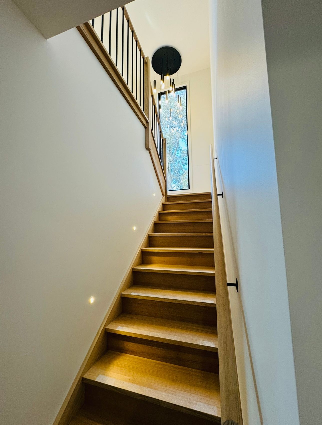 Wooden staircase leading upwards, with a window at the top and a black light fixture — Crampton Painting & Decorating Pty Ltd In Maiden Gully, VIC