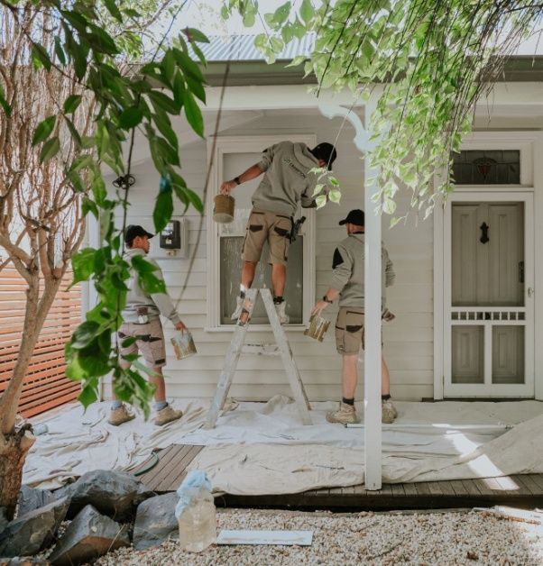 A Group Of Men Are Painting A White House — Crampton Painting & Decorating Pty Ltd In Maiden Gully, VIC