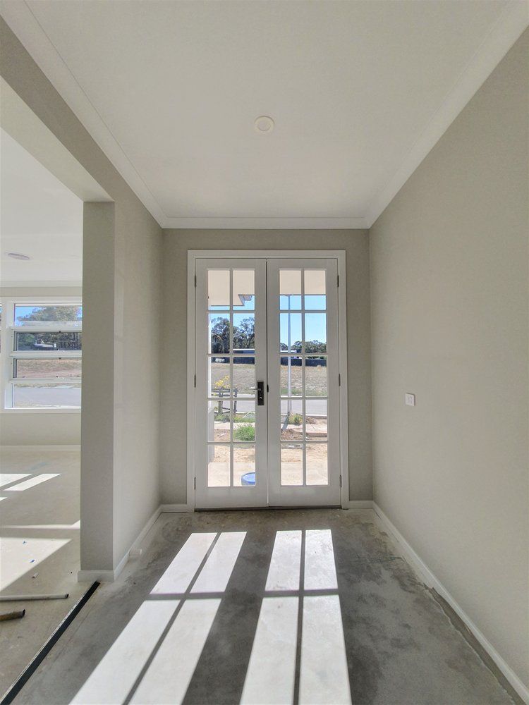 A Hallway With A White Door And A Window — Crampton Painting & Decorating Pty Ltd In Maiden Gully, VIC