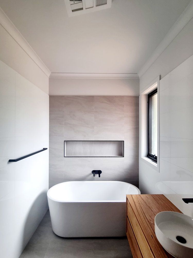 A Bathroom With A Bathtub , Sink And Window — Crampton Painting & Decorating Pty Ltd In Maiden Gully, VIC