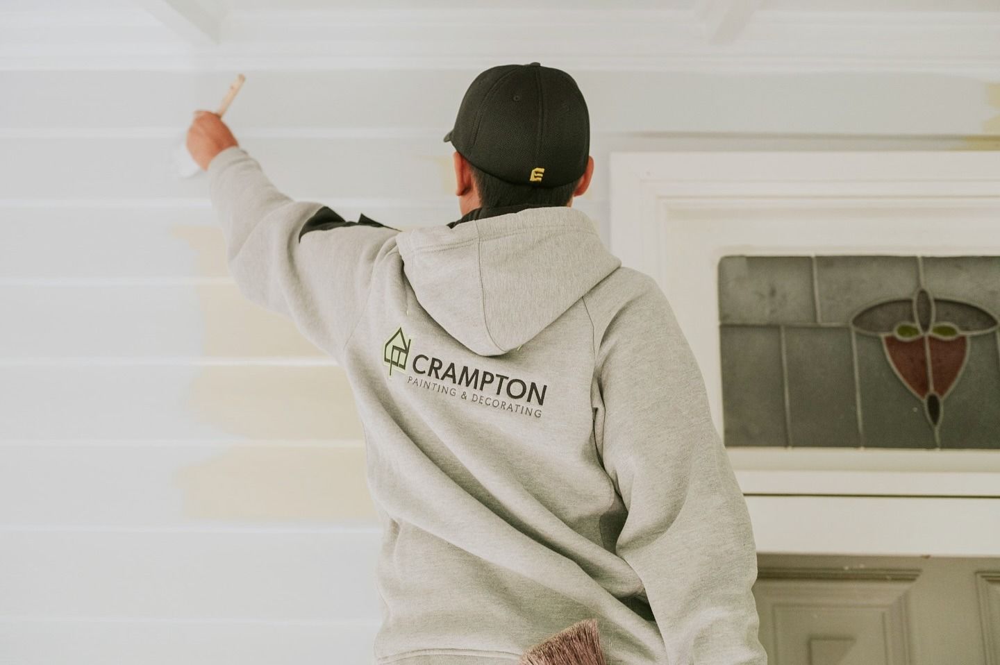A Man Is Painting A Window In A Room With Lots Of Windows — Crampton Painting & Decorating Pty Ltd In Daylesford, VIC