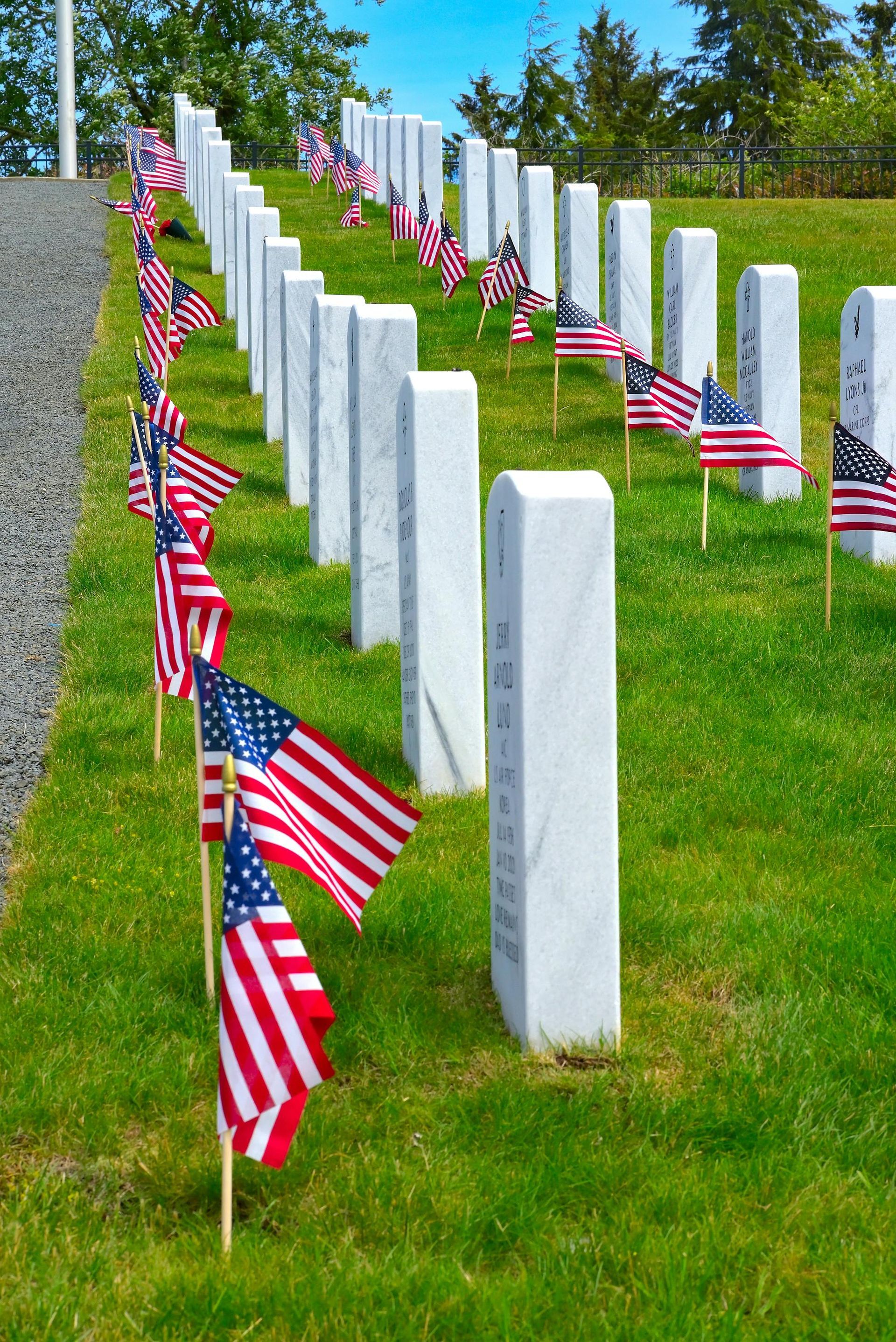 A woman is putting her hand on an American flag at a funeral.