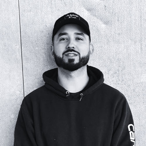 A man with a beard is wearing a hat and a black shirt.