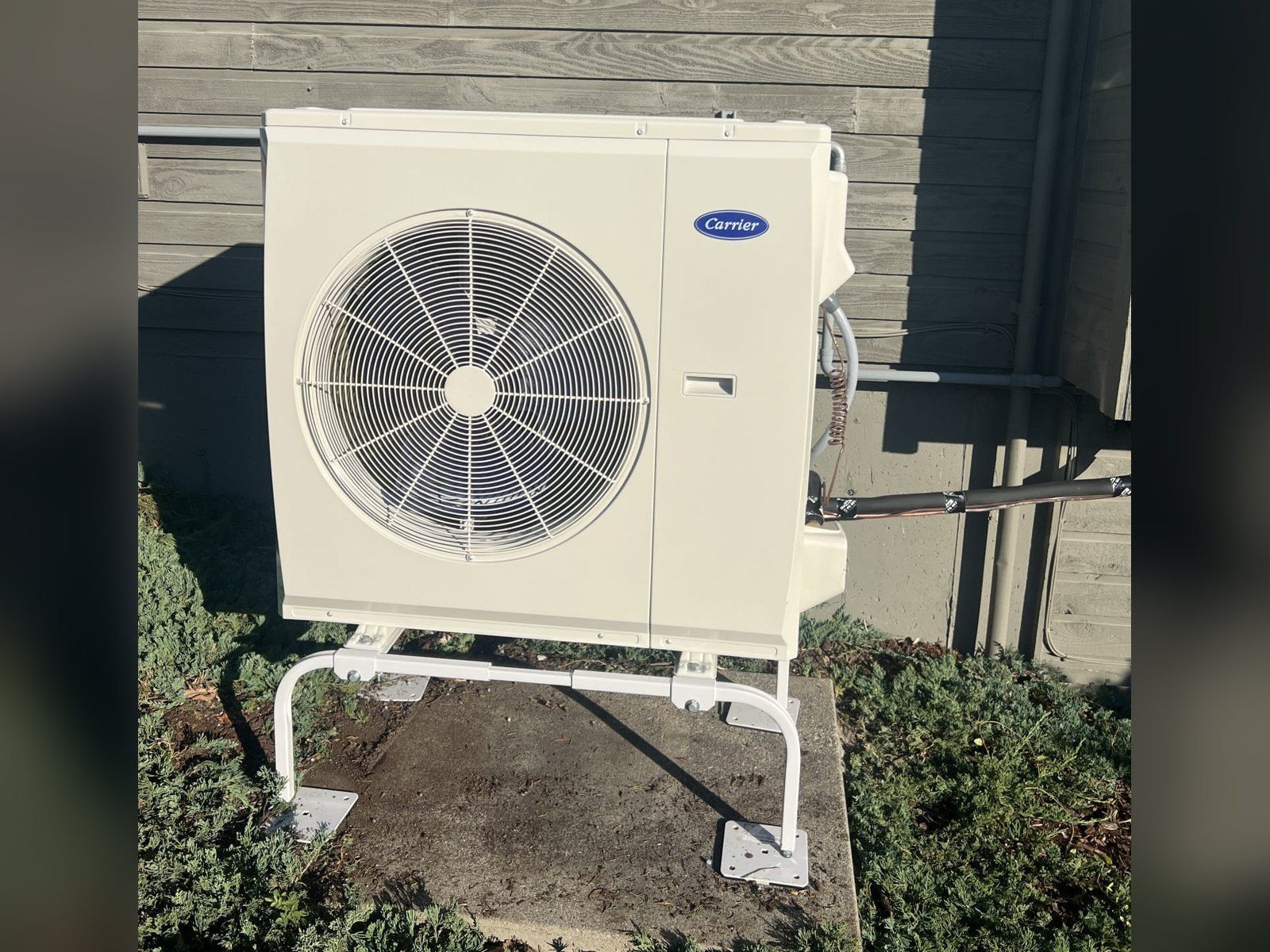 New Carrier heat pump on a raised stand and concrete pad, installed by Alpine Aire at a home in Manson, WA