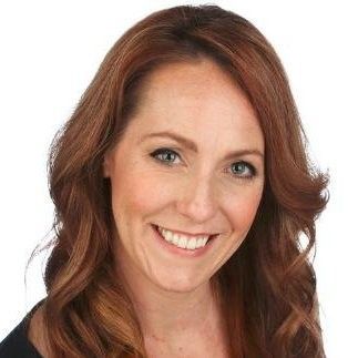 Smiling woman with shoulder-length auburn hair on a white background