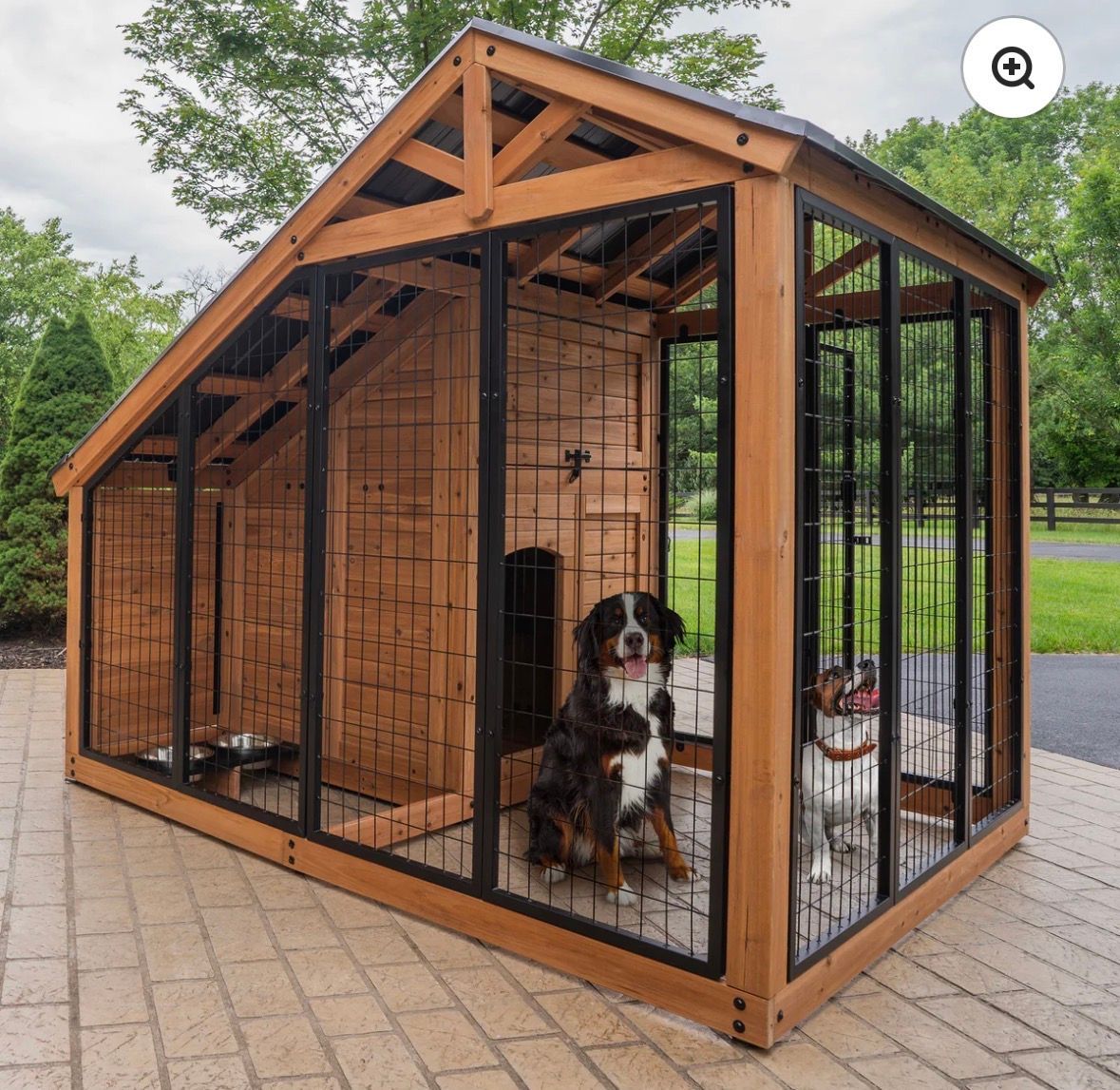 Wooden outdoor dog kennel with black metal bars, showing two dogs inside on a brick patio.