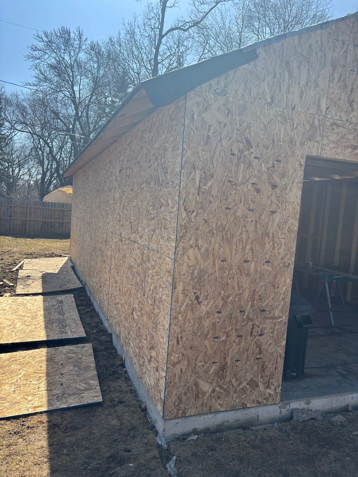 Partially built shed with OSB sheathing and open doorway on a concrete foundation