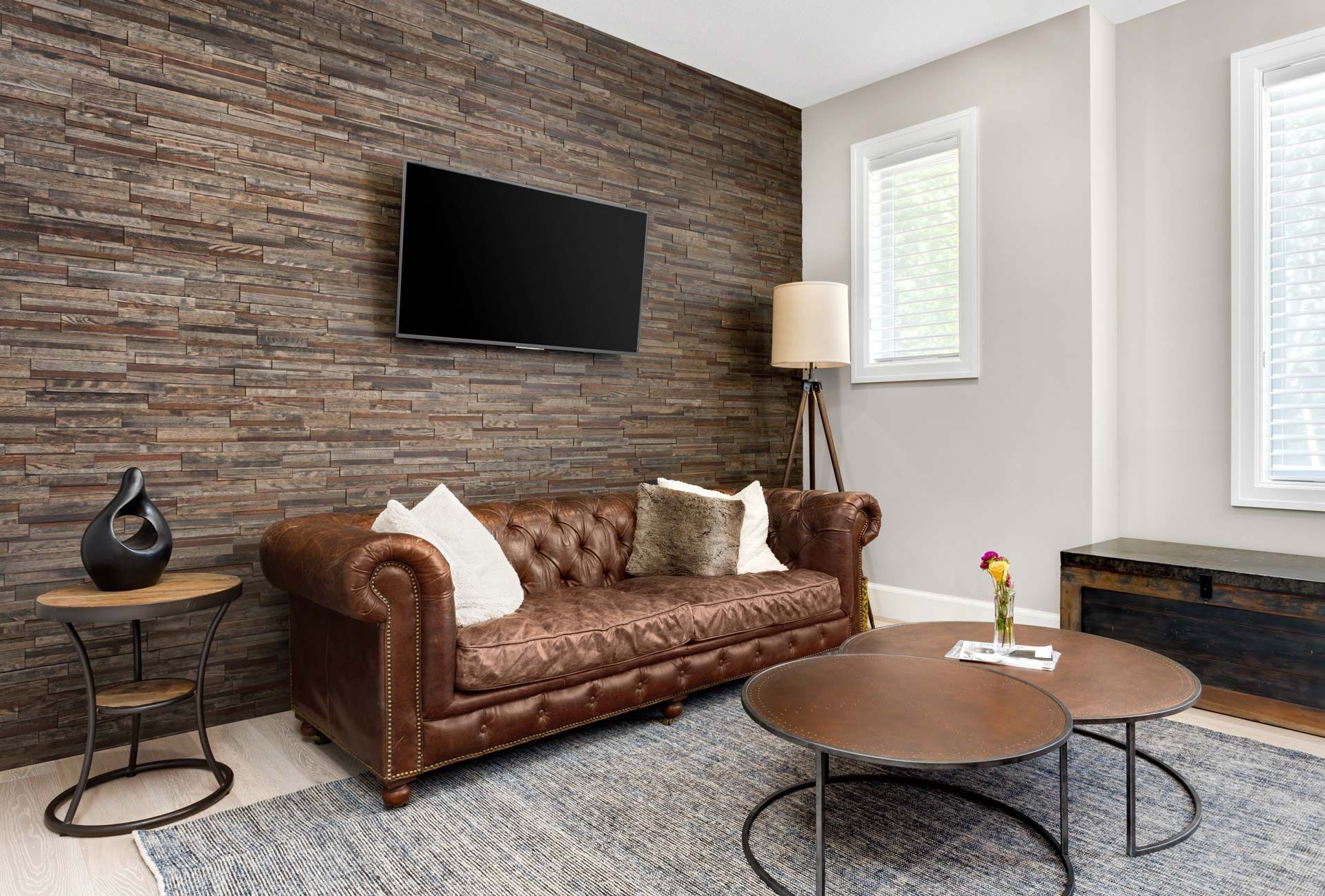A living room with a brown couch , two coffee tables , and a flat screen tv.