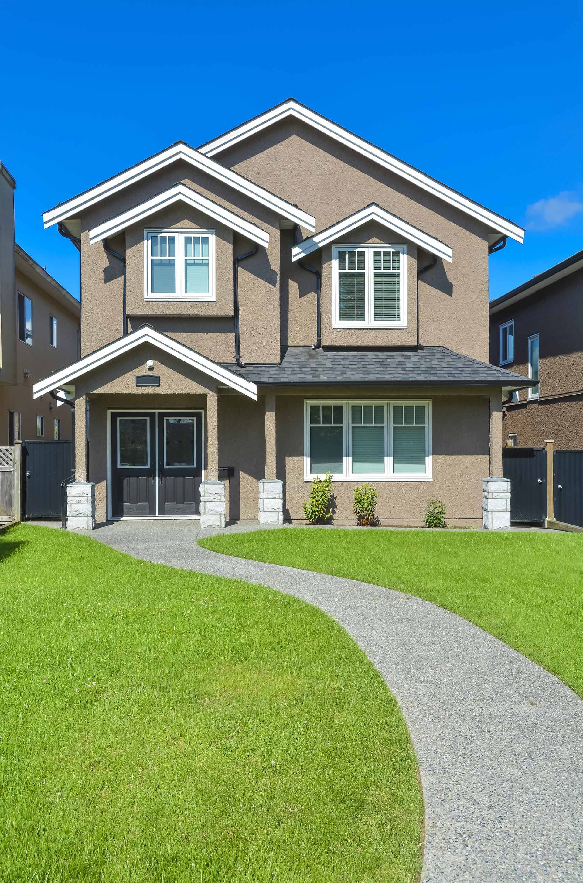 A large house with a lush green lawn and a walkway leading to it