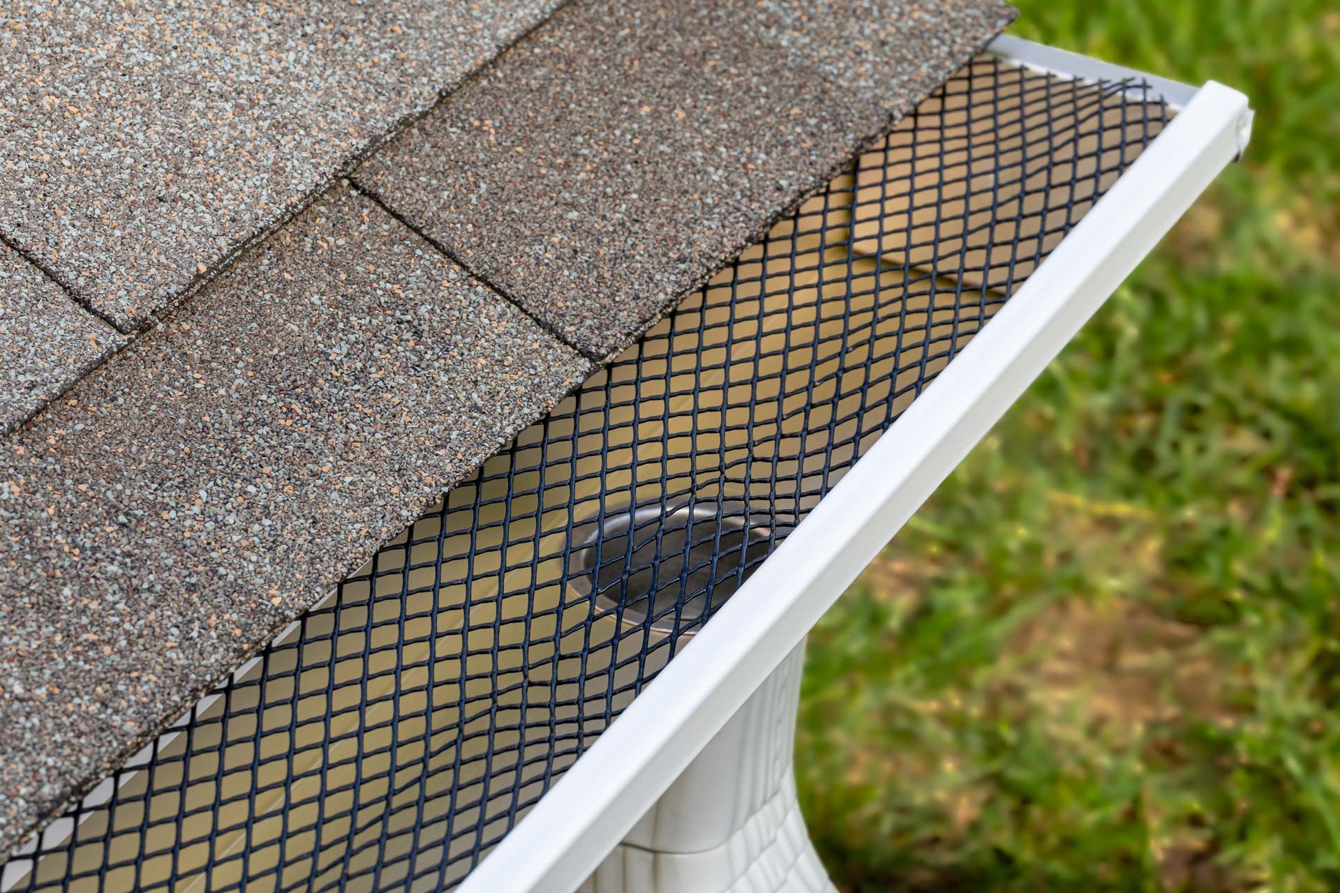 A close up of a gutter with a roof in the background