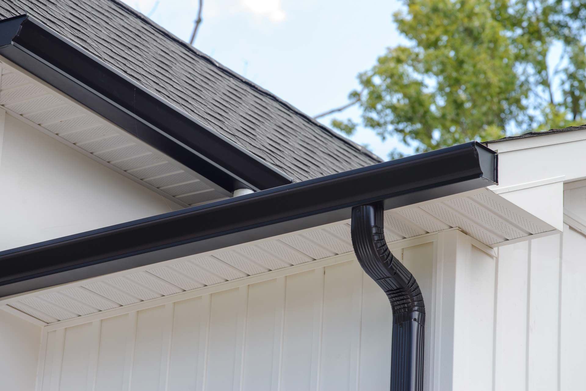 A black gutter is on the side of a white house