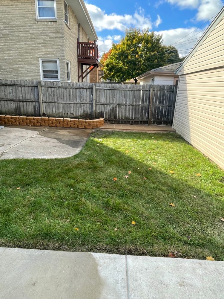 A backyard with a fence and a house in the background
