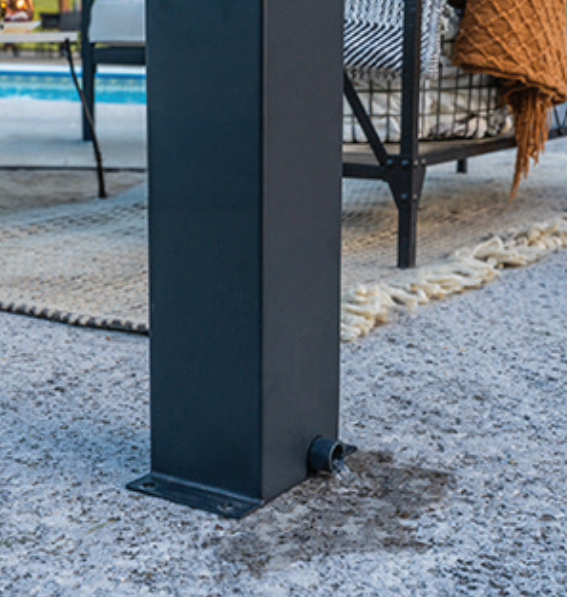 Black metal table leg on a speckled floor beside an outdoor rug and wicker chair