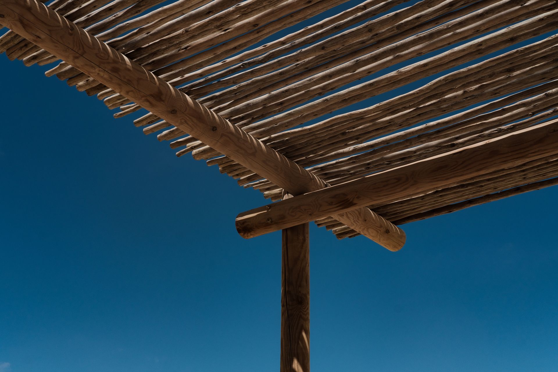 Wooden pergola beams against a clear blue sky