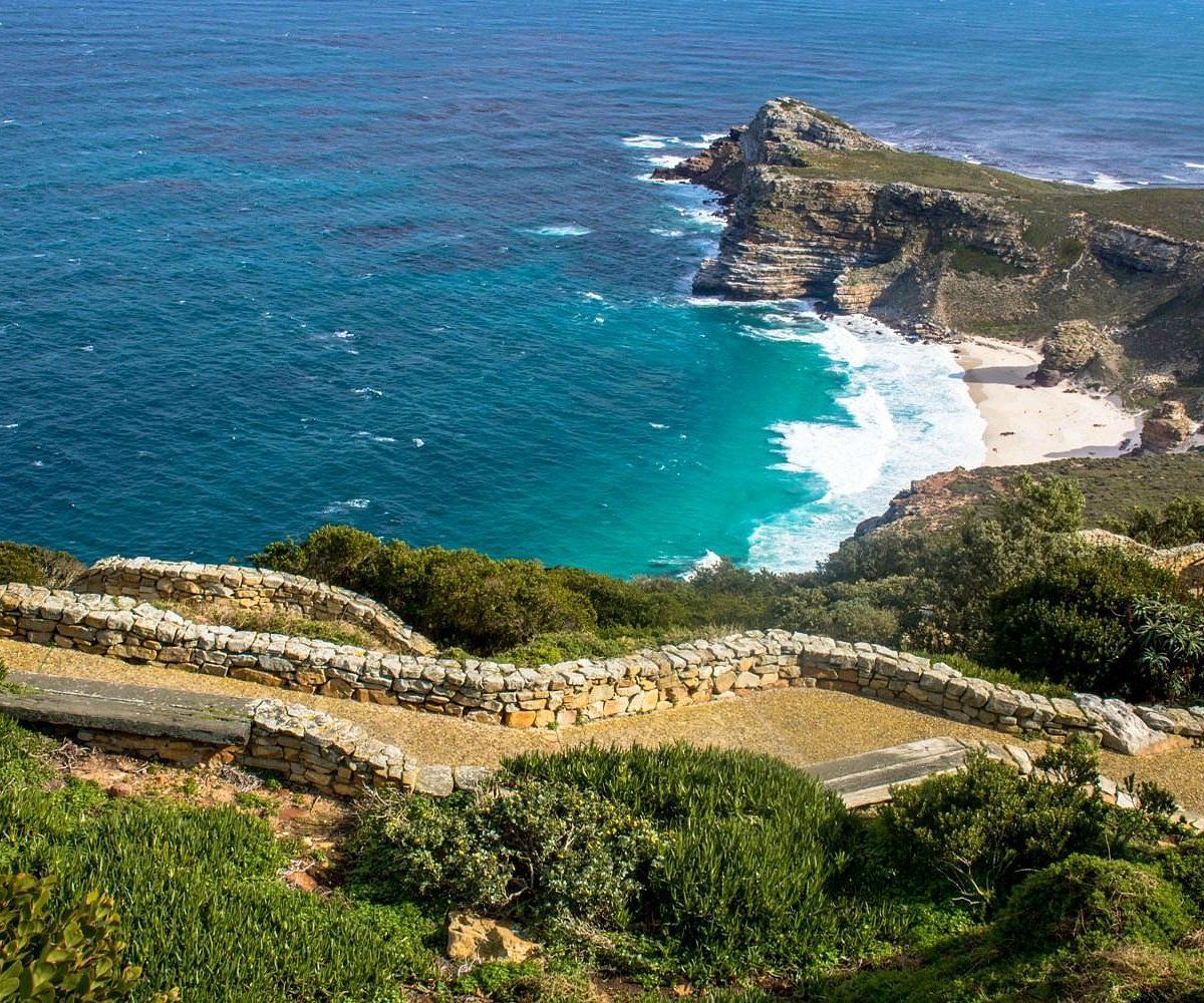 Uma vista de uma praia do topo de uma falésia com vista para o oceano.