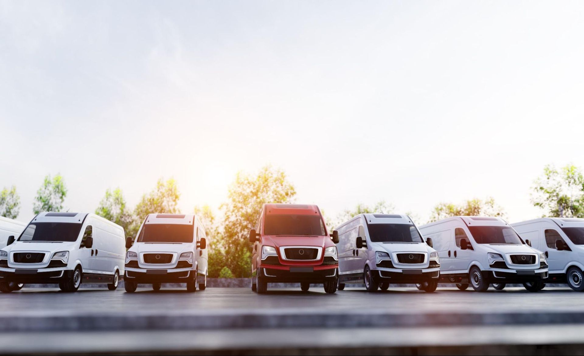 A row of delivery vans are parked in a row on the side of the road.