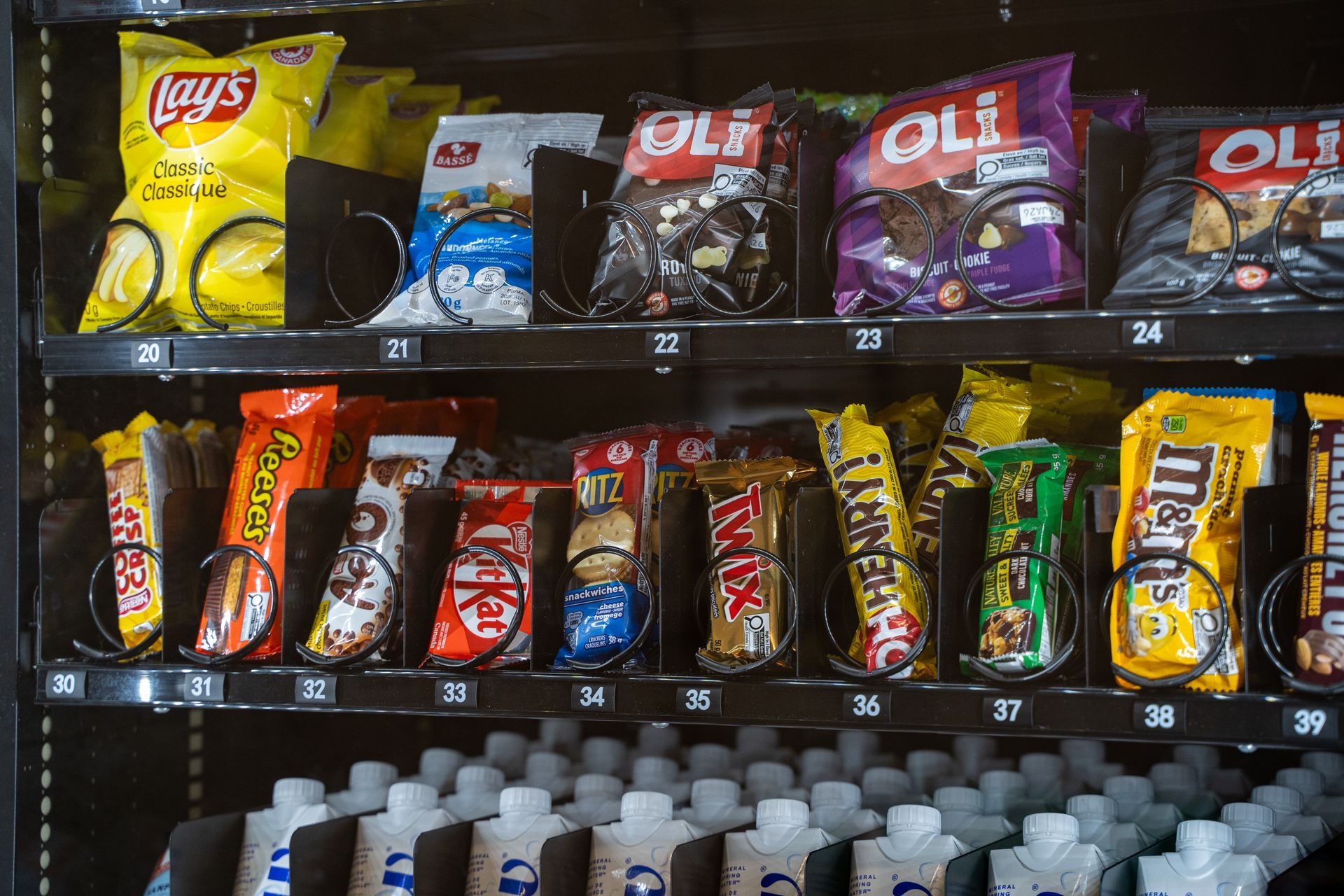 Des sachets de chips assorties, notamment des Lay's et des OLI, sont présentés sur une étagère de magasin.