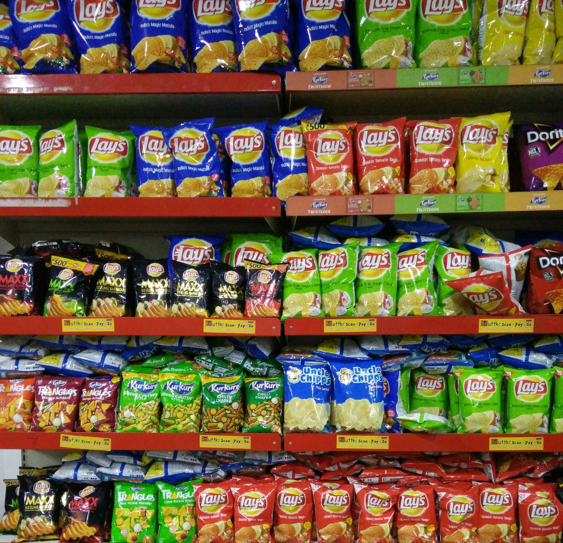 Rayons de sachets de chips Lay's de différentes marques dans une supérette.