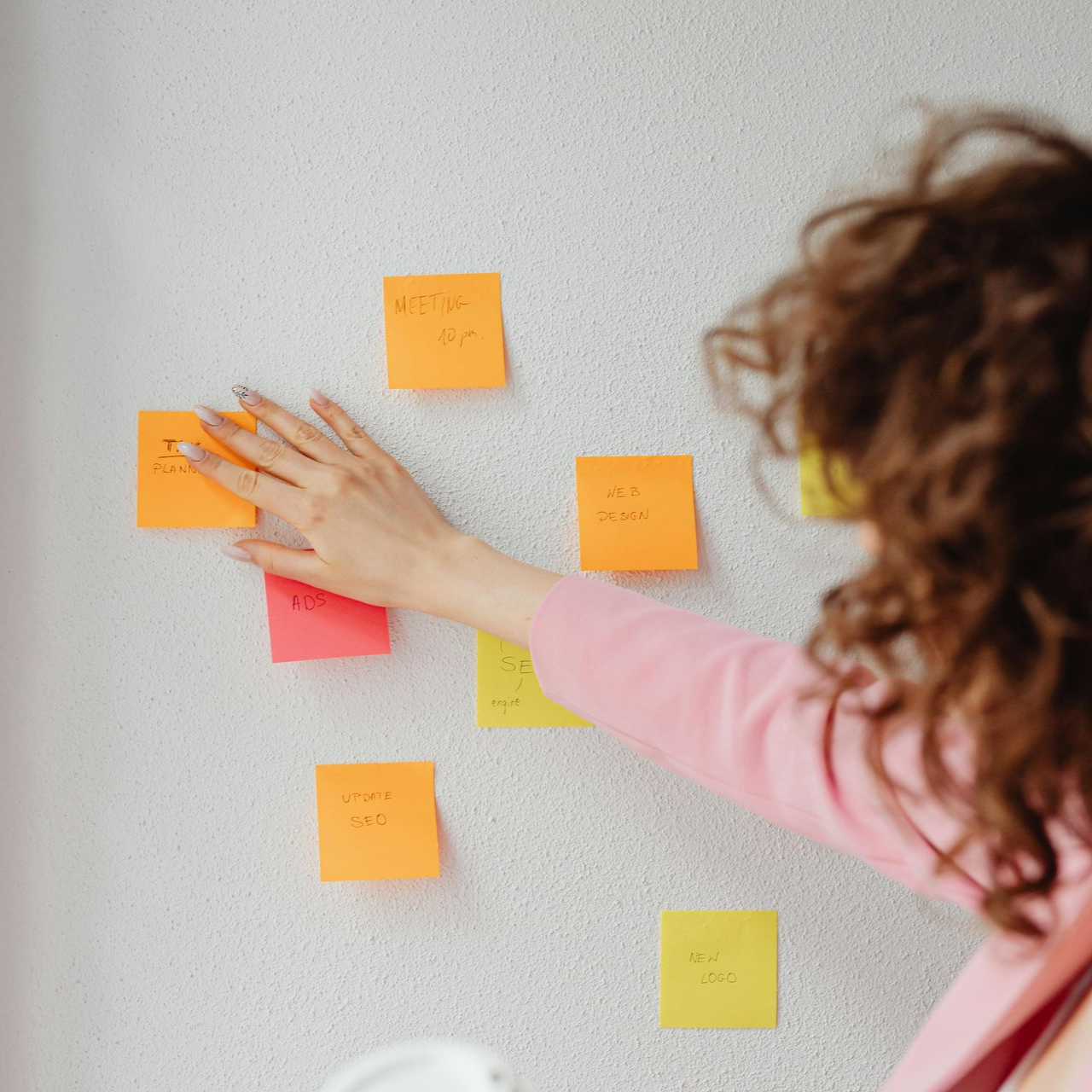 Une personne colle des post-it colorés sur un mur lors d'une séance de brainstorming