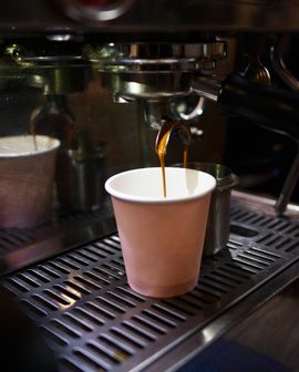 Un expresso est versé dans un gobelet en papier brun à l'aide d'une machine à café.