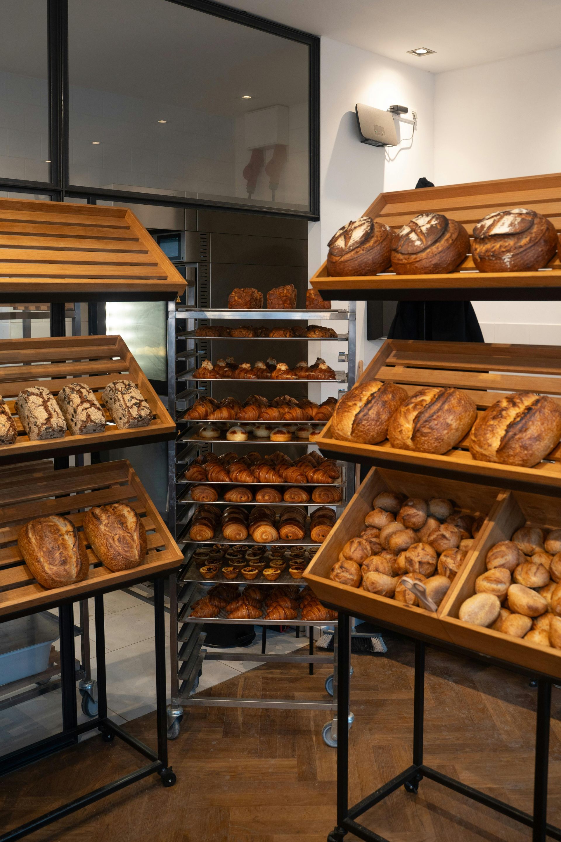 Vitrine de boulangerie présentant un assortiment de pains et de pâtisseries sur des étagères en bois