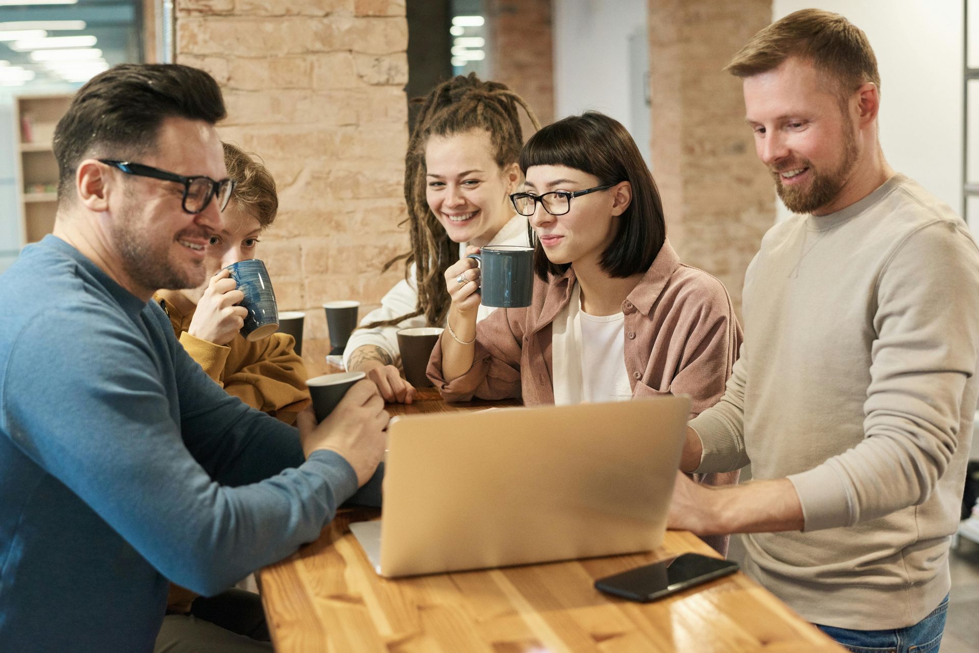 Des personnes étaient rassemblées autour d'un ordinateur portable à une table, souriant et discutant 