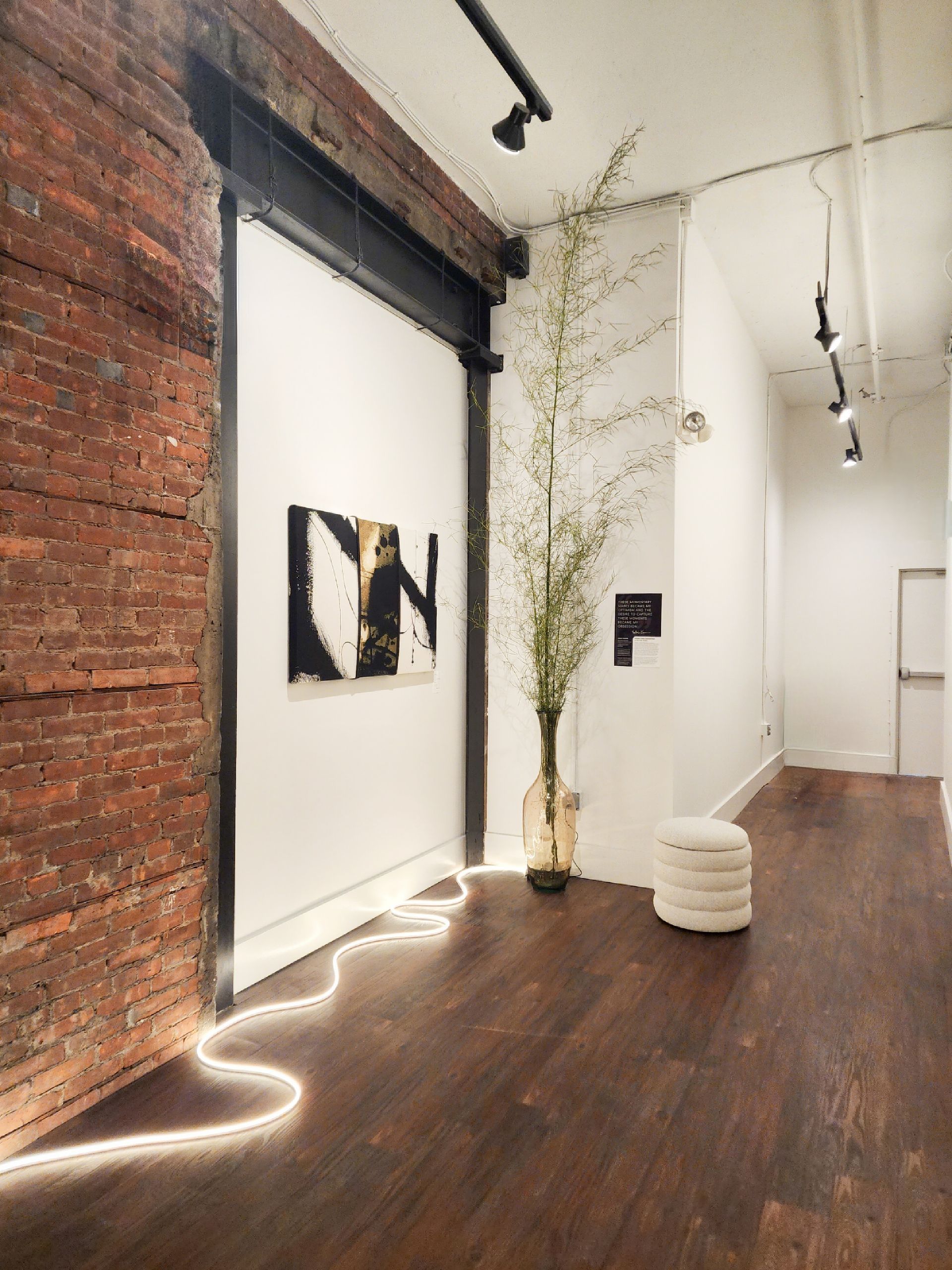 A hallway with a brick wall and a painting with the letter n on it