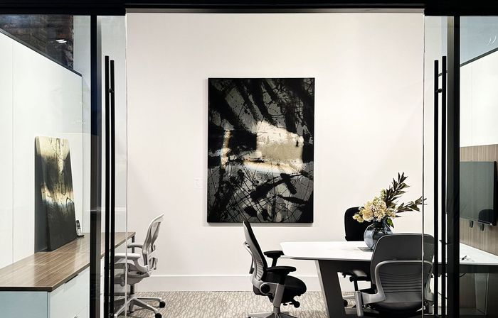 A conference room with a table and chairs and a painting on the wall.