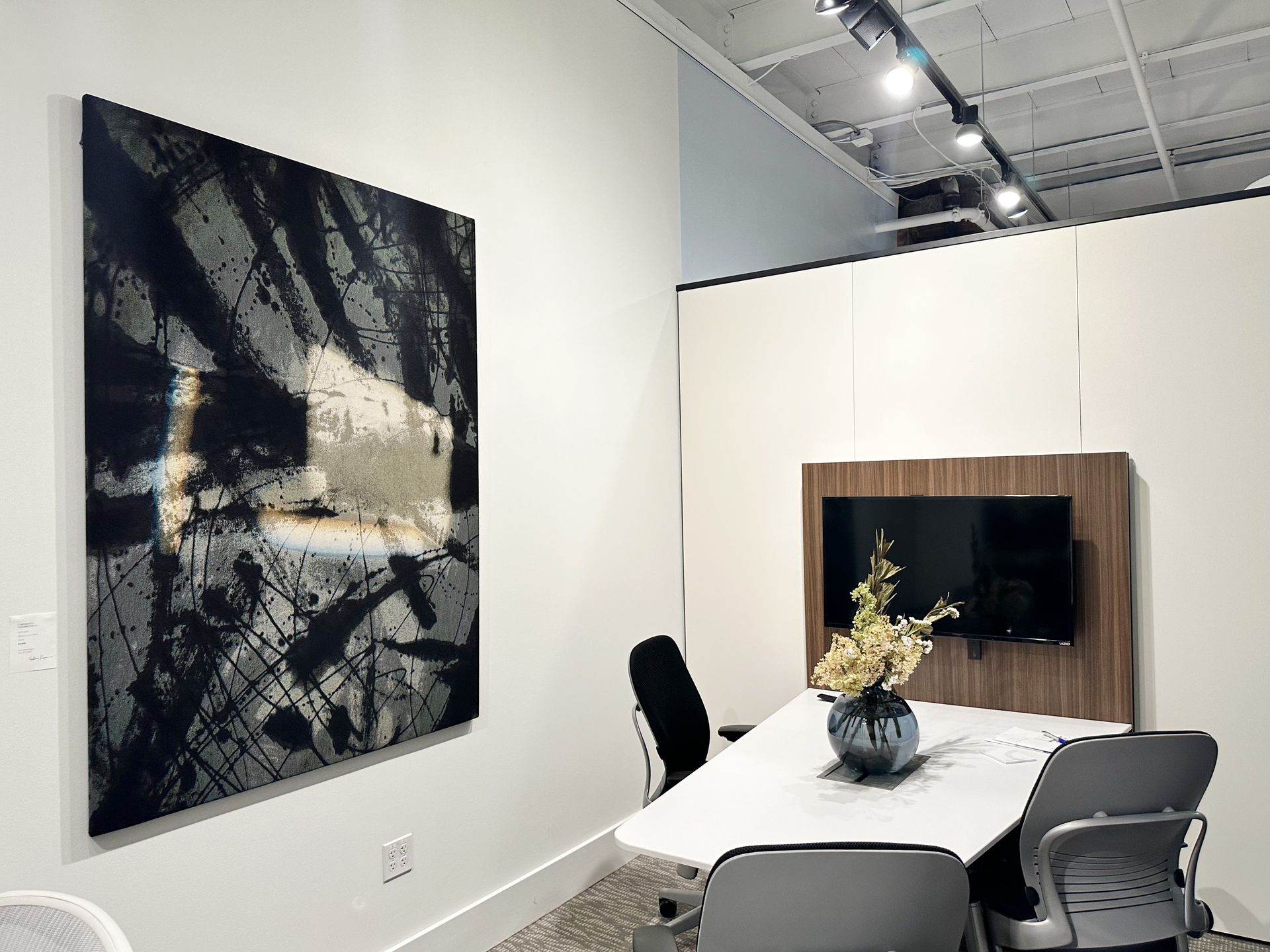 A conference room with a table and chairs and a large painting on the wall.