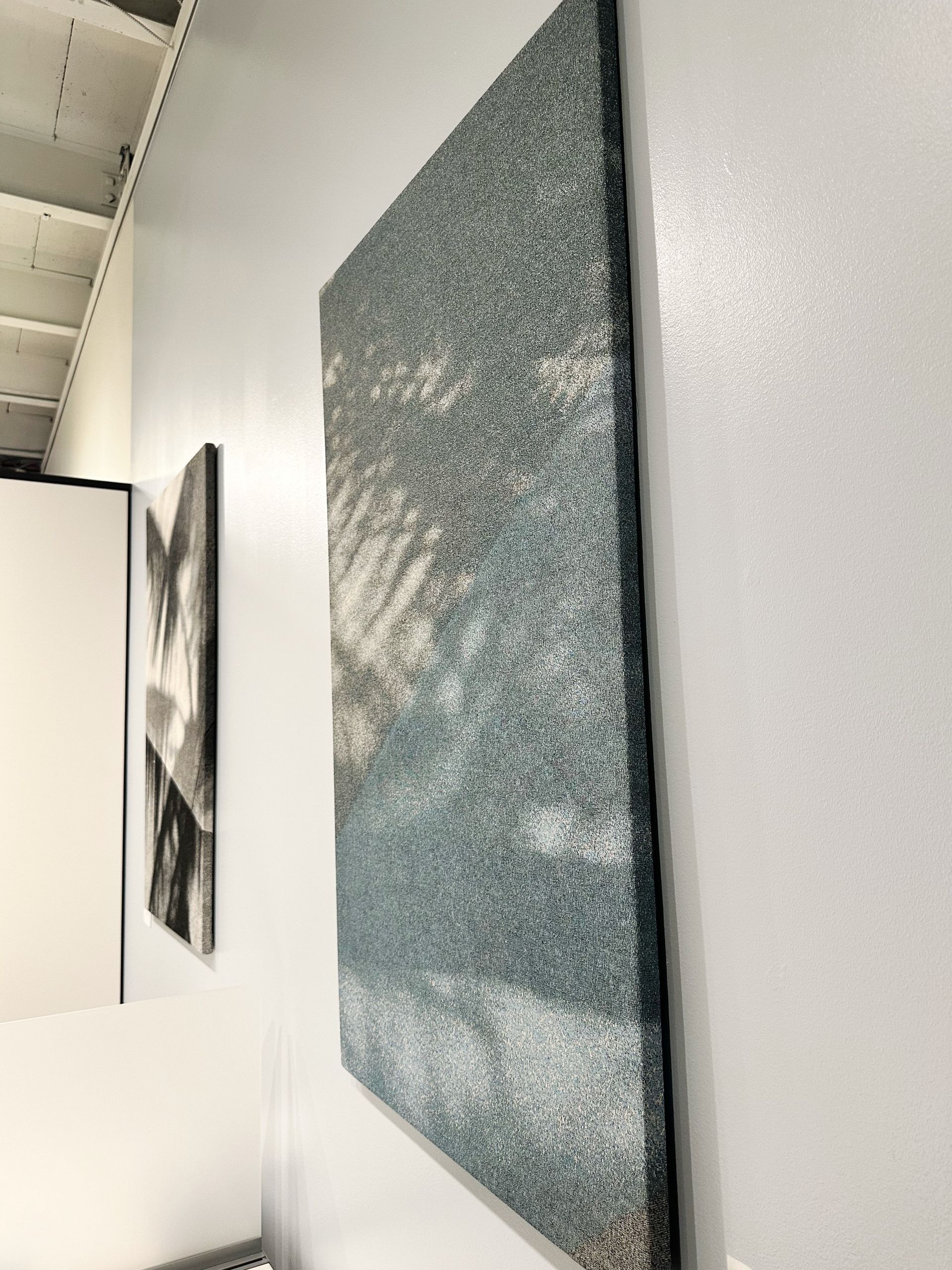 A painting is hanging on a white wall in a room.