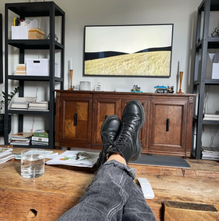 A person 's feet rest on a wooden table in a living room