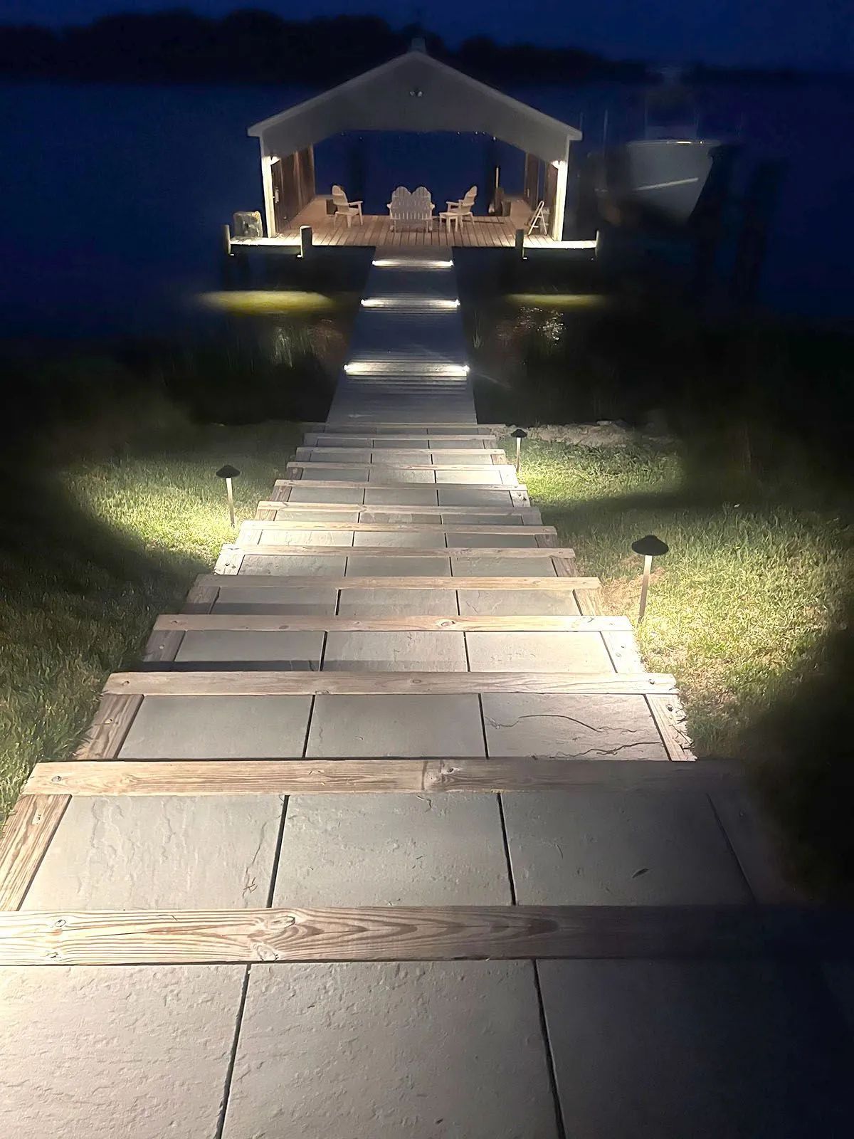 Lit stone walkway leading to a softly lit outdoor pavilion at night