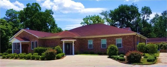 Single-story brick house with a large driveway and landscaped front yard under a clear sky