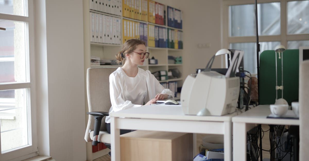 Young woman with glasses working on computer for bookkeeping at desk