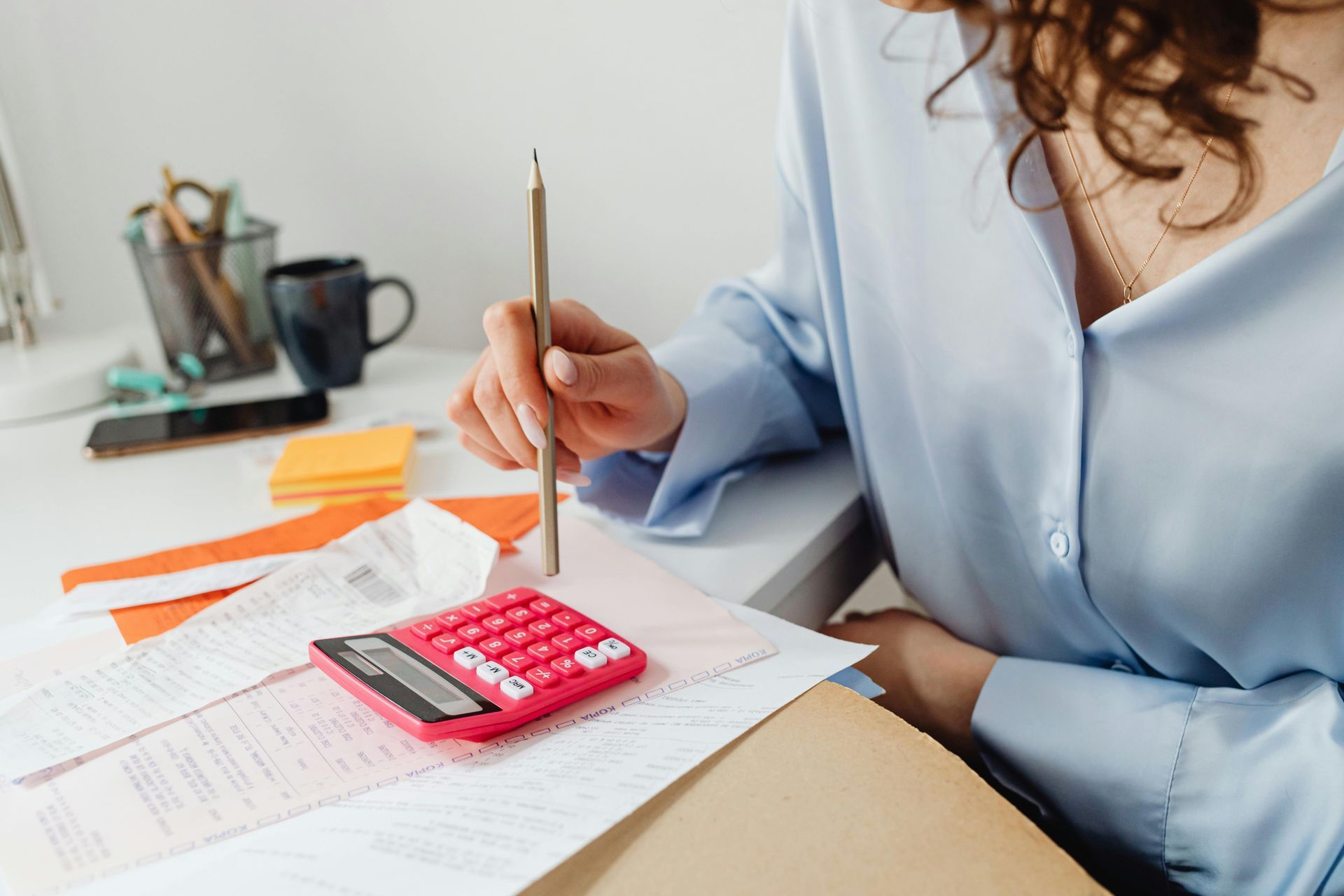 Woman using calculator and pencil to review bookkeeping documents