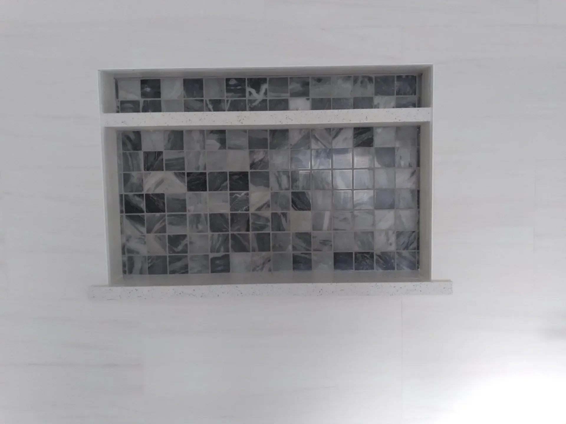 Small rectangular mosaic-tiled window set into a light wall.