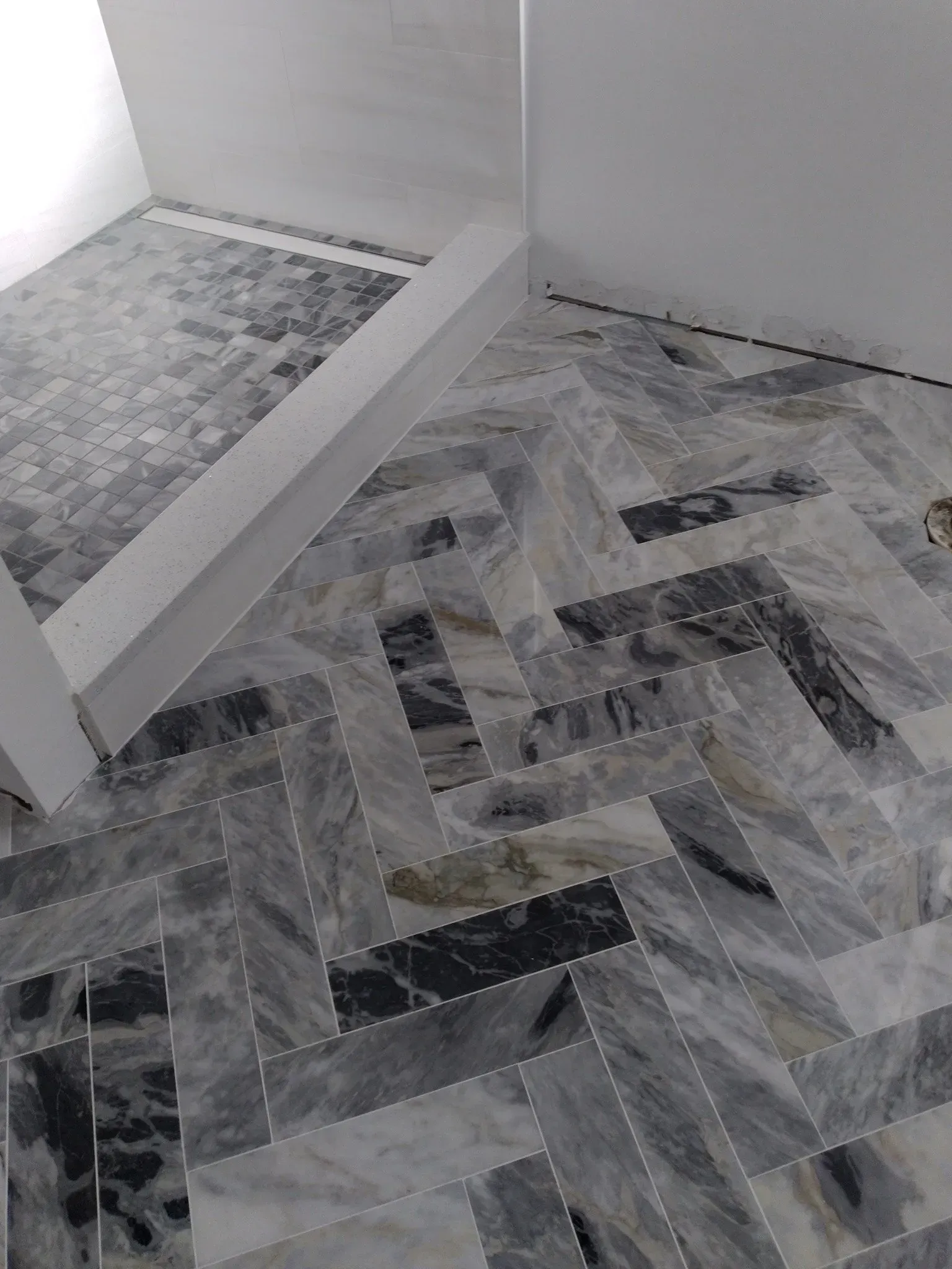 Gray and black patterned tile floor with a white stair edge and wall corner