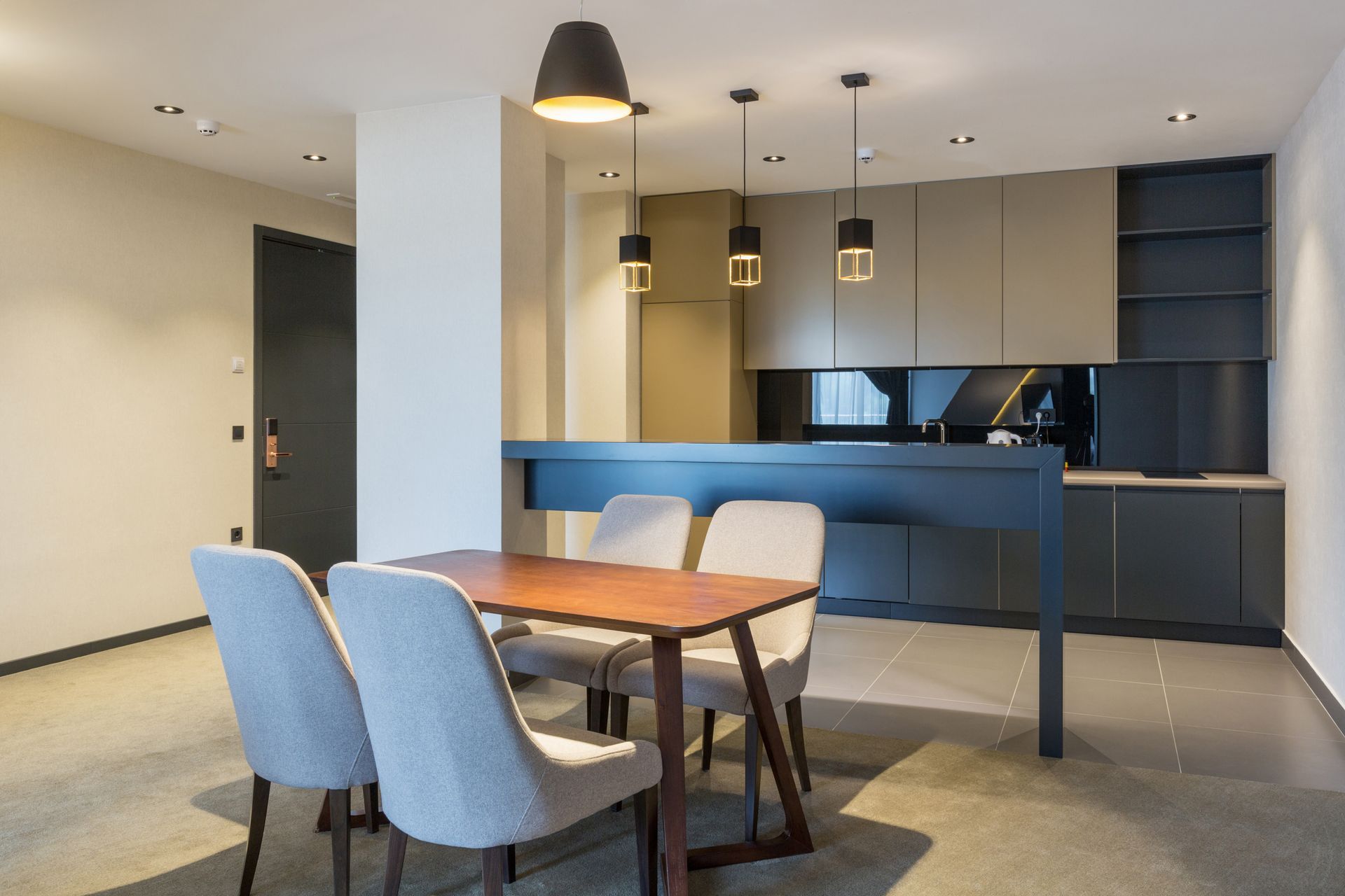 Modern dining area with a wooden table, blue chairs, pendant lights, and a blue kitchen wall unit. Modern dining area with a wooden table, blue chairs, pendant lights, and a blue kitchen wall unit.