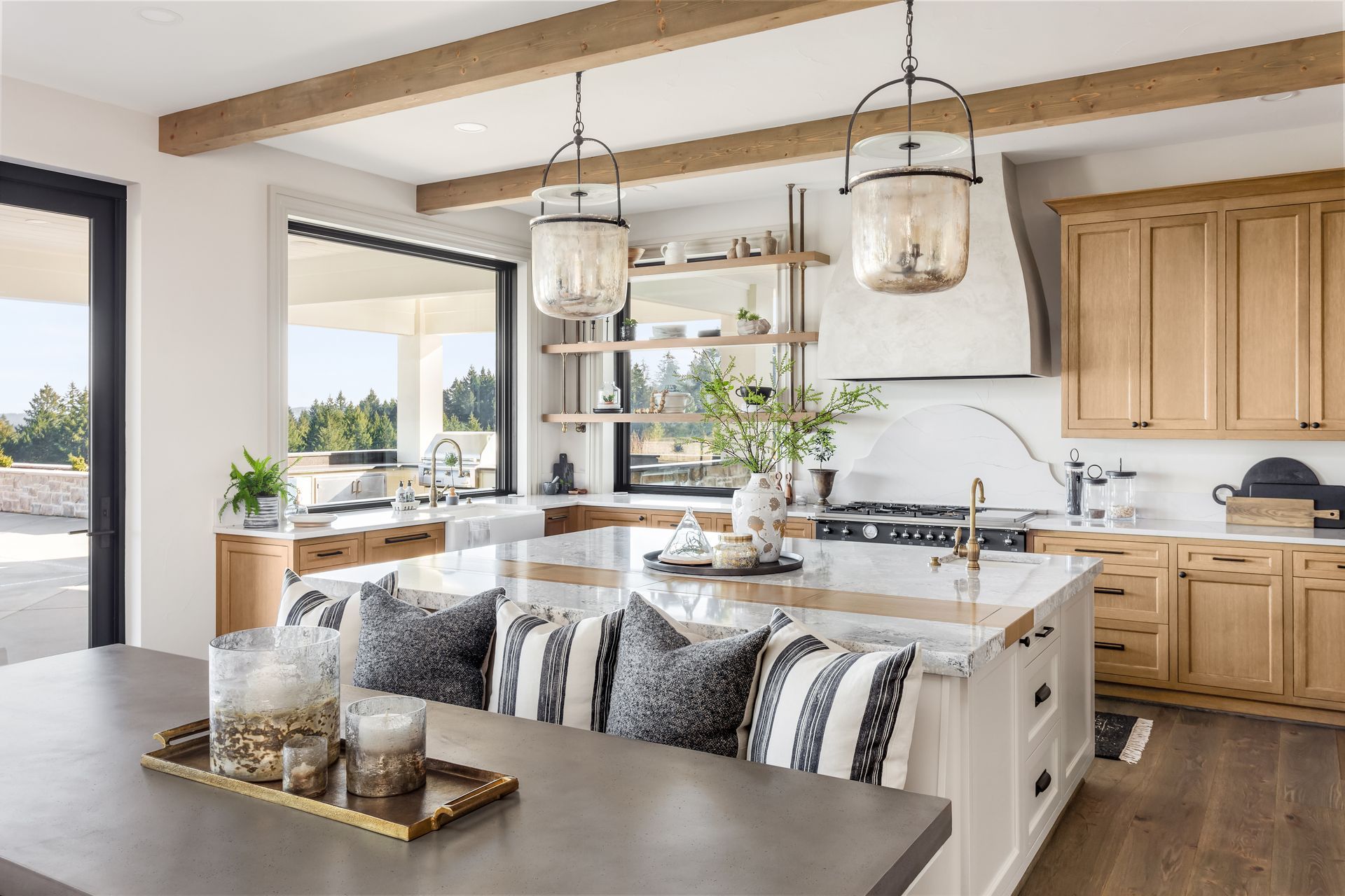 Bright modern kitchen with island, pendant lights, wood cabinets, and large windows overlooking outdoors Bright modern kitchen with island, pendant lights, wood cabinets, and large windows overlooking outdoors