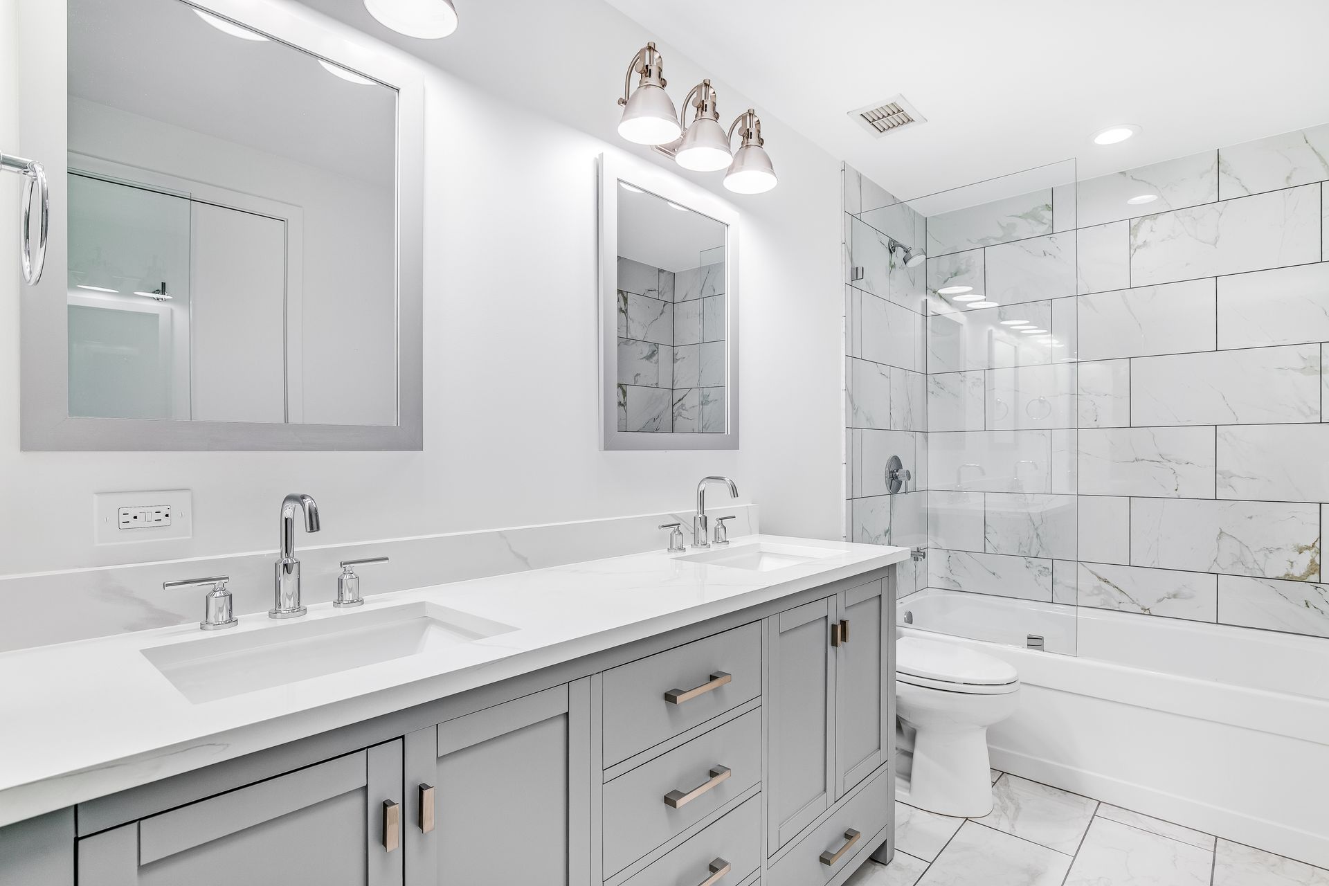 Bright white bathroom with double vanity, large mirrors, and glass-enclosed shower. Bright white bathroom with double vanity, large mirrors, and glass-enclosed shower.