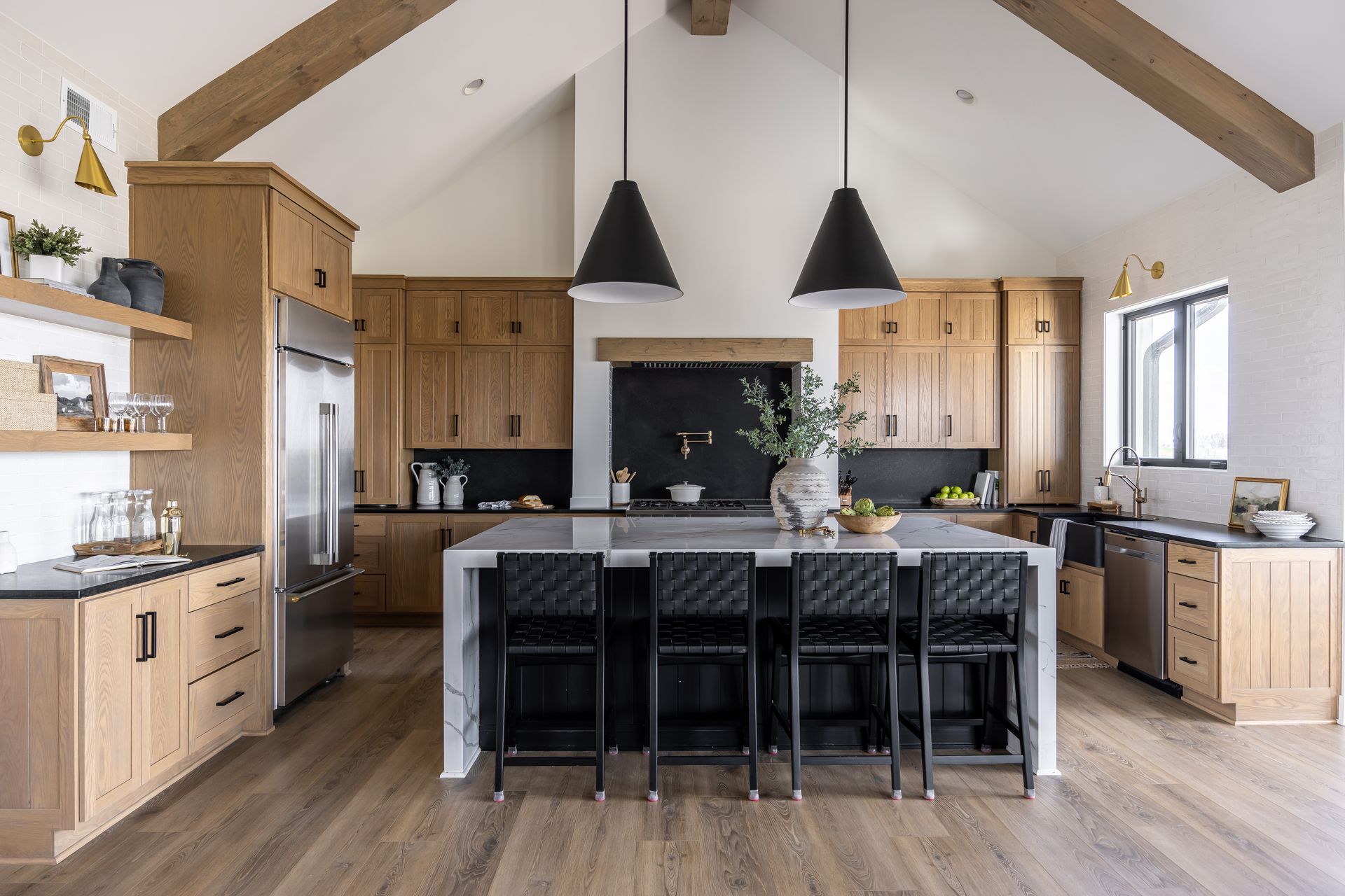 Modern kitchen with wood cabinets, large island, black pendant lights, and vaulted ceiling Modern kitchen with wood cabinets, large island, black pendant lights, and vaulted ceiling
